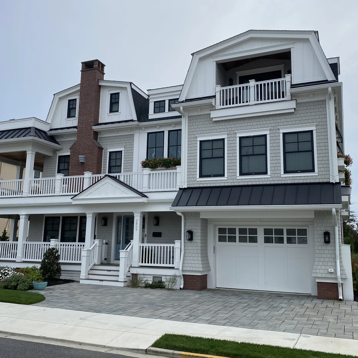 Coastal home with dark metal roofing and white dormers